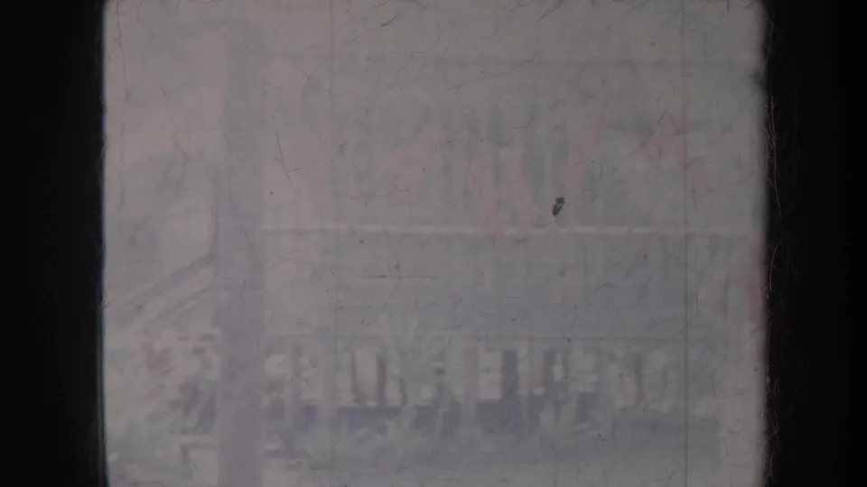 Soft 1967 Honolulu 8mm frame with faint distant silhouettes and rail-like forms behind heavy fading and scratches.