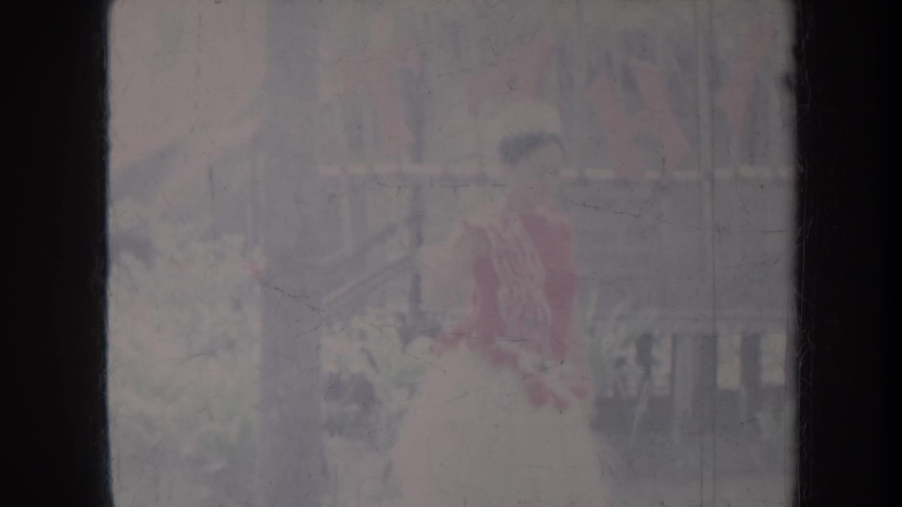 Dancer in red and pale clothing outdoors, partly faded by film exposure.