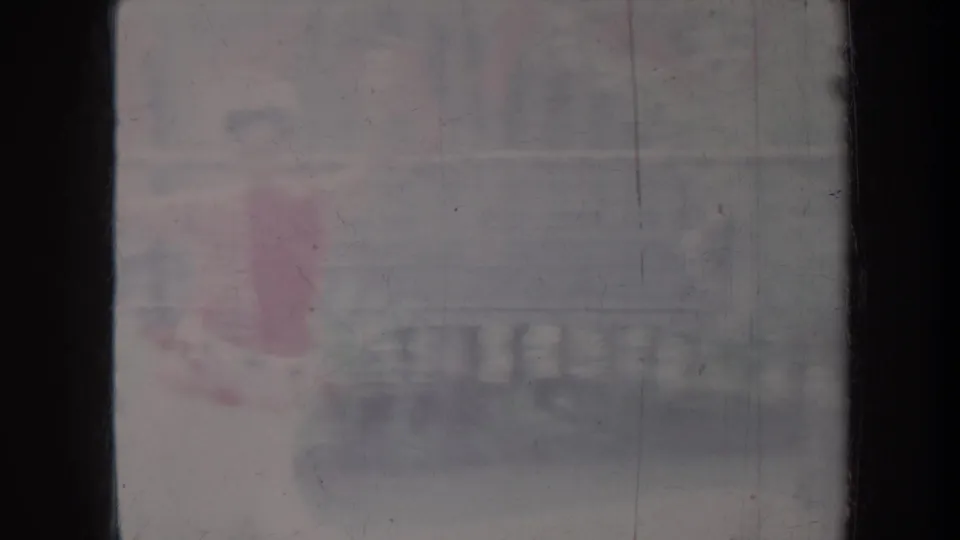 Faded 1967 Honolulu home-movie frame with a dancer moving in red and pale clothing before an outdoor backdrop.