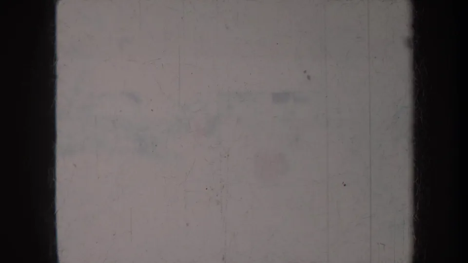 Faded 8mm frame from the Honolulu resort clip, with much of the scene washed out and bordered by dark vertical film edges.