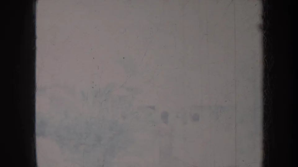 Soft, damaged 1967 Honolulu frame with faint seated figures and outdoor ground barely visible through faded film.
