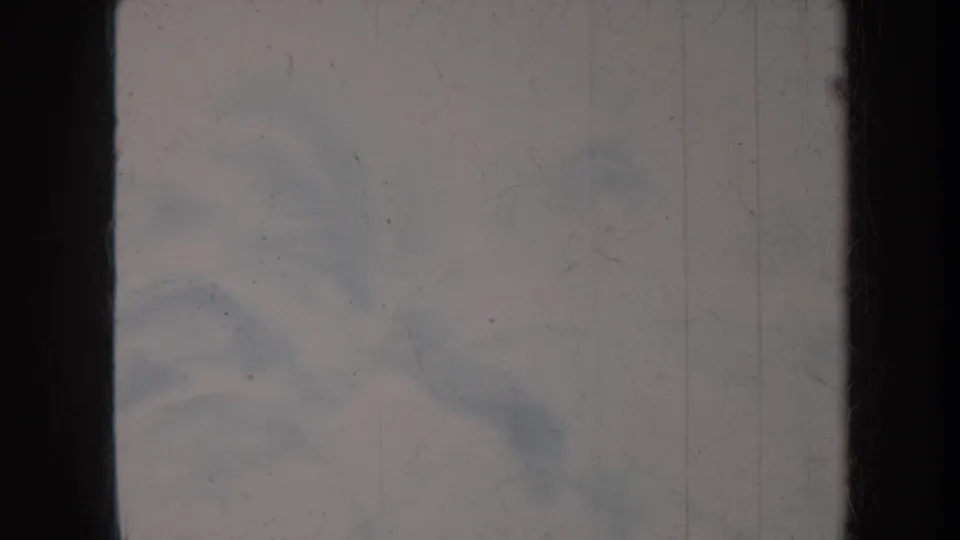 Faded 8mm Honolulu frame with indistinct people and outdoor forms visible beneath scratches and exposure loss.