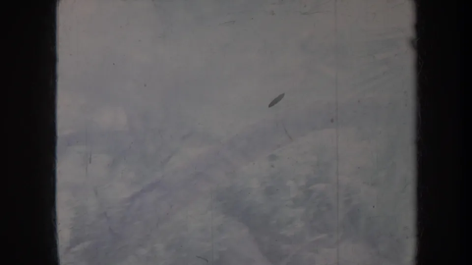Low-contrast 1967 Honolulu home-movie frame showing dark borders, visible film wear, and soft tropical vegetation shapes.