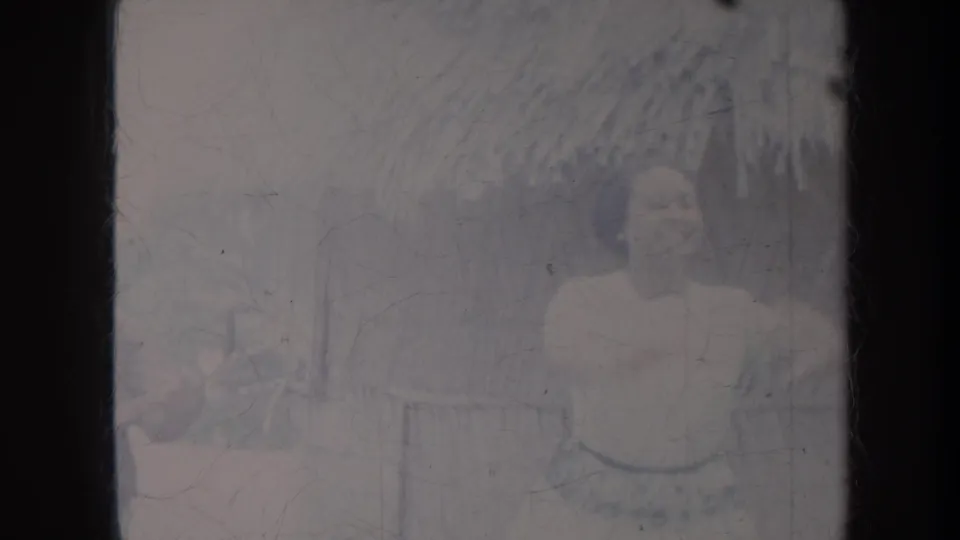 1967 Honolulu outdoor frame with the woman facing forward near foliage as the guitarist remains partly visible at the edge.