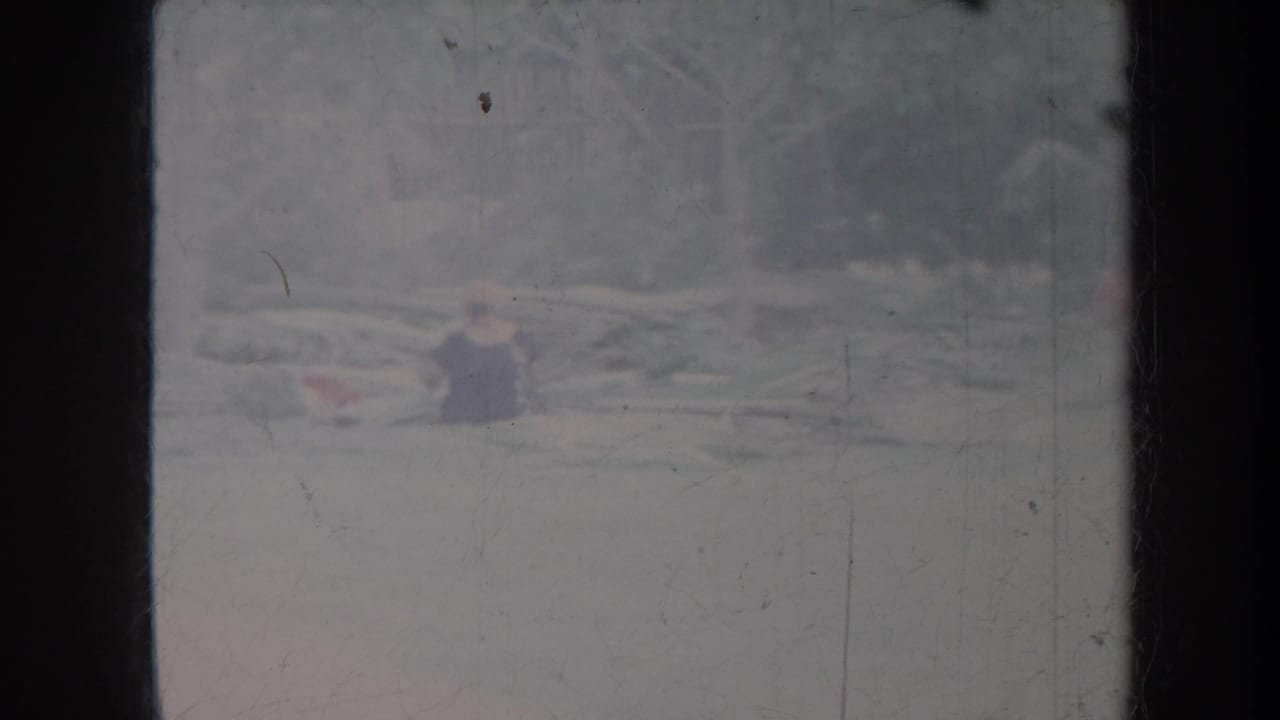 Blurred outdoor view with a person in dark clothing near pale horizontal debris.