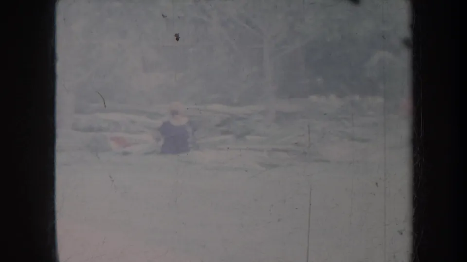 Faded Honolulu 1967 frame with a small person in dark clothing near pale logs or debris, seen through scratched 8mm film.