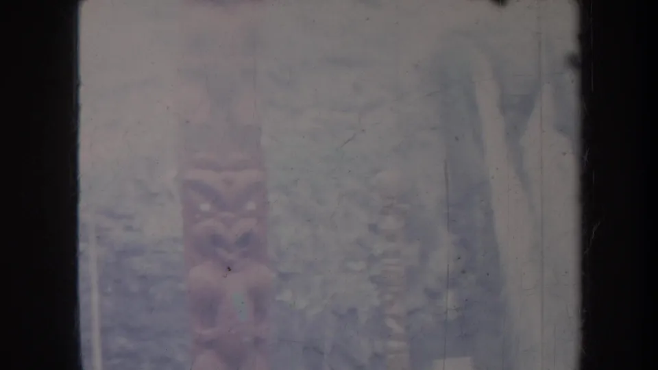 Faded 1967 Honolulu 8mm frame showing pale falling water or cliff face amid dark rock and foliage, softened by film wear.