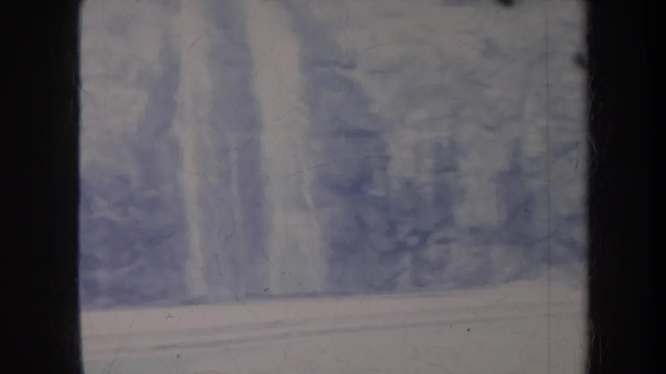 Faded 1967 Honolulu travel frame showing a pale waterfall-like form and dense greenery behind a horizontal wall or path.