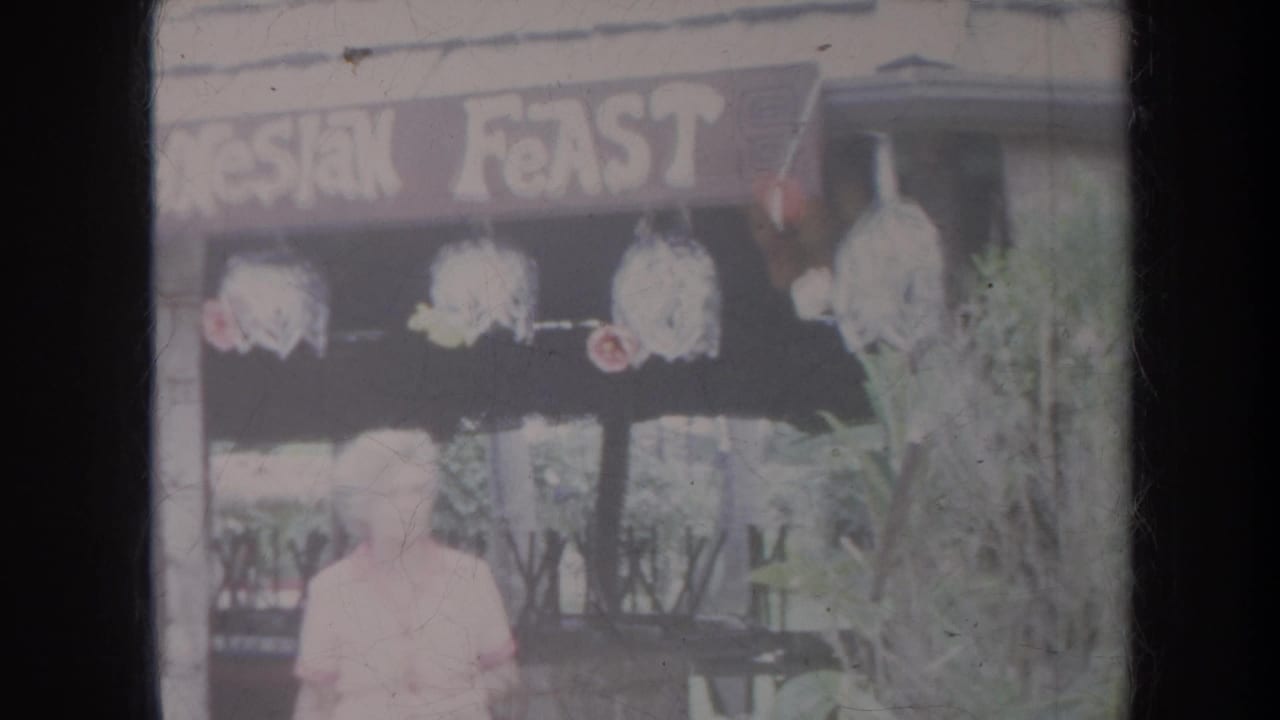 Woman walking in front of a Polynesian Feast sign and decorated stall.