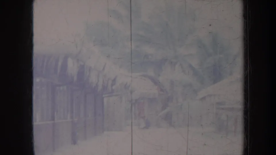 Faded 1967 8mm frame with palms, a low building, and window-like borders in a tropical travel setting.