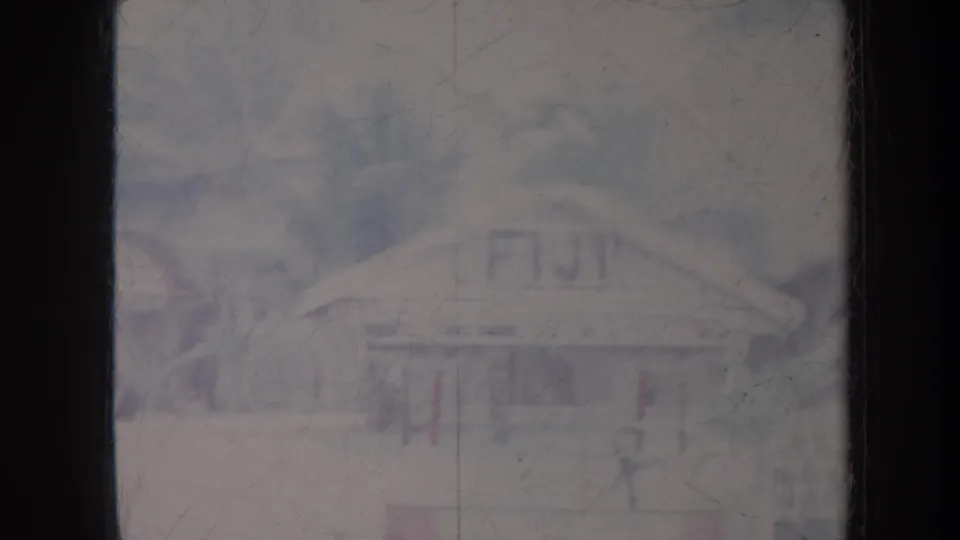 1967 8mm travel frame showing a small building with FIJI painted on the roof amid palms and soft film haze.