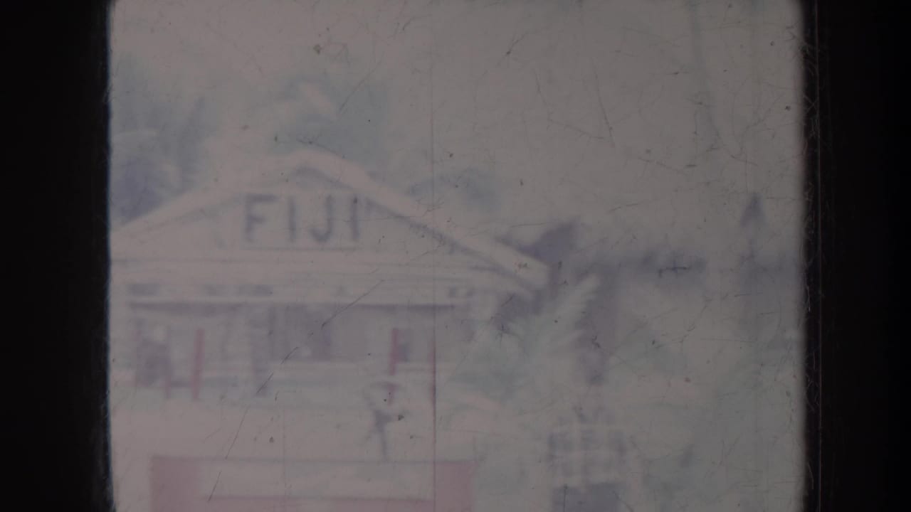 Faded view of a hut facade with FIJI lettering, palm foliage, and soft film scratches.