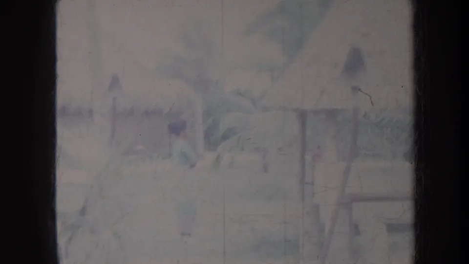 1967 Honolulu travel frame showing a palm-lined village walkway with hut structures and a partly visible person in the middle distance.