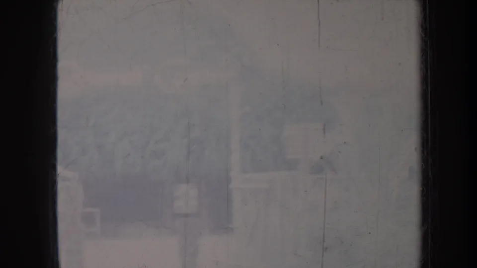1967 Honolulu 8mm frame showing a hazy exterior view through dark window framing and scratched glass.