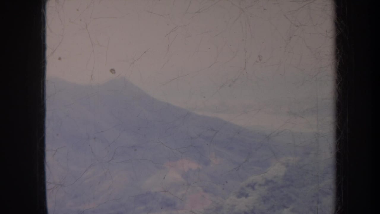 Hazy mountain ridges seen through a scratched, faded 8mm film frame.