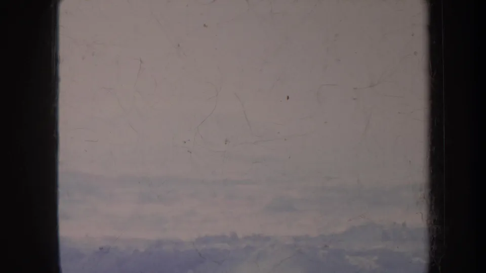 Faded 8mm Honolulu travel footage frame with faint distant ridges, pale haze, scratches, and dust across the scan.
