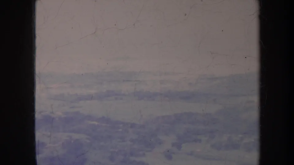 1967 Hawaii home-movie view from an aircraft window, looking toward a patchy landscape of trees, fields, and roads.