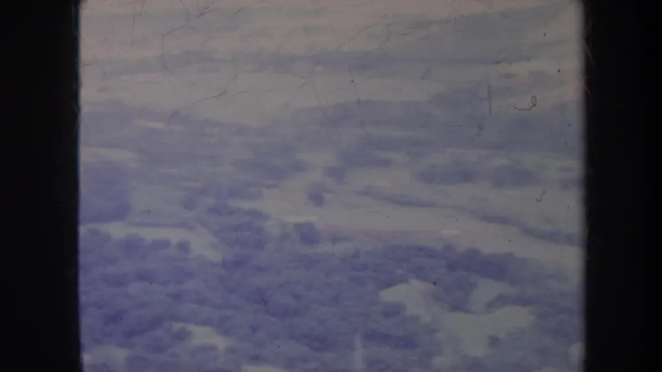 1967 Hawaii aerial frame showing a soft, faded view of trees, fields, and roads below dark aircraft-window dividers.
