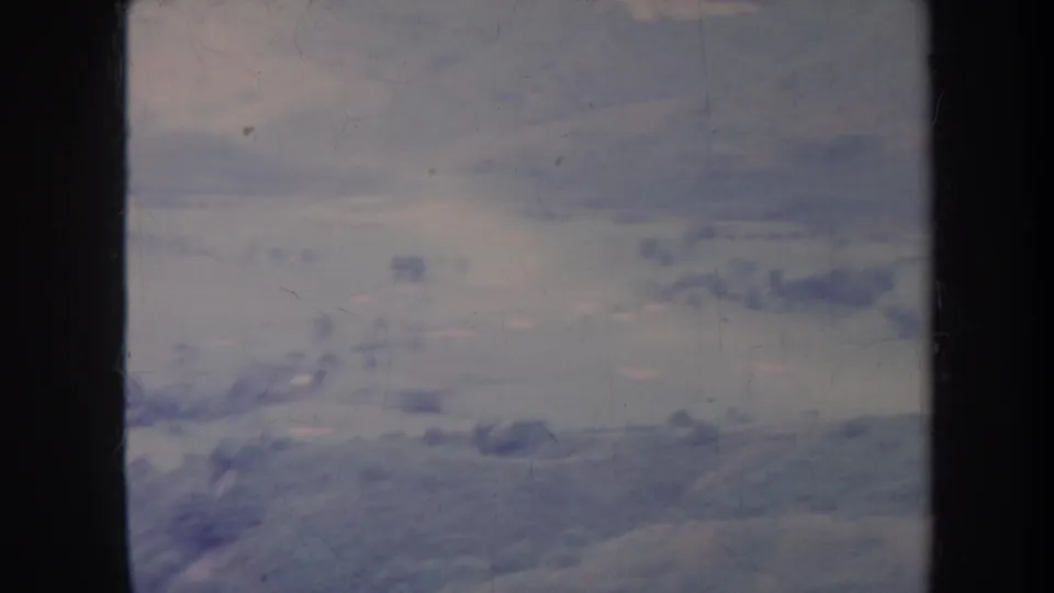 1967 Honolulu-area aerial frame with soft open valley terrain, faint ridges, sparse trees, and blue-purple 8mm color shift.