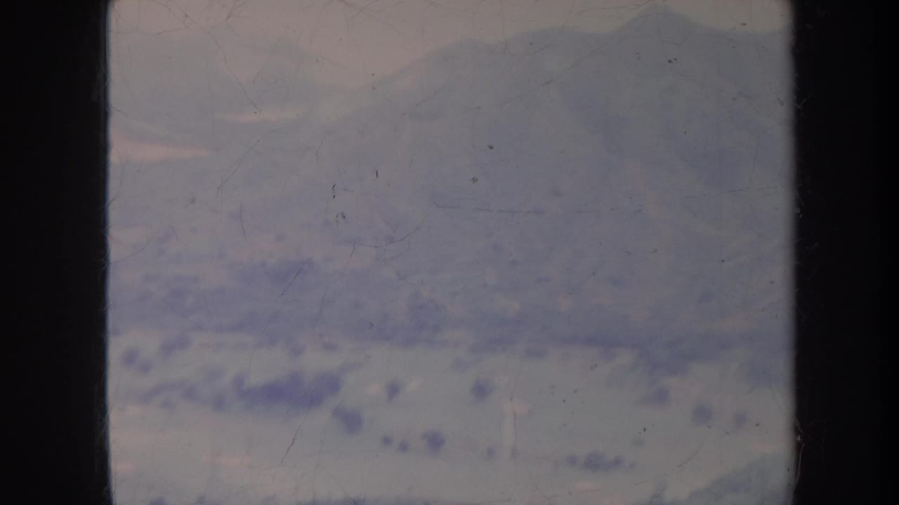 Hazy mountain landscape under a pale sky with dark 8mm frame borders.