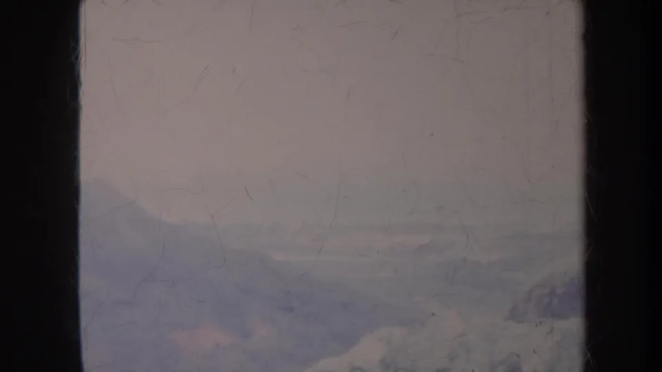 1967 Honolulu 8mm frame with a faint hillside landscape, pale sky, and pronounced surface scratches.