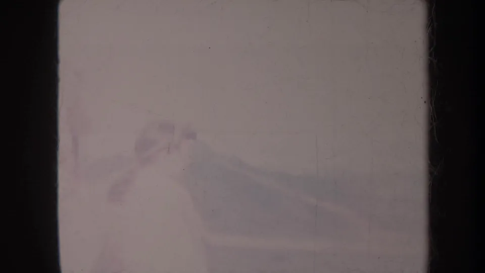 1967 Honolulu home-movie frame with a faint partial figure near a balcony, distant hills, and heavy film wear.