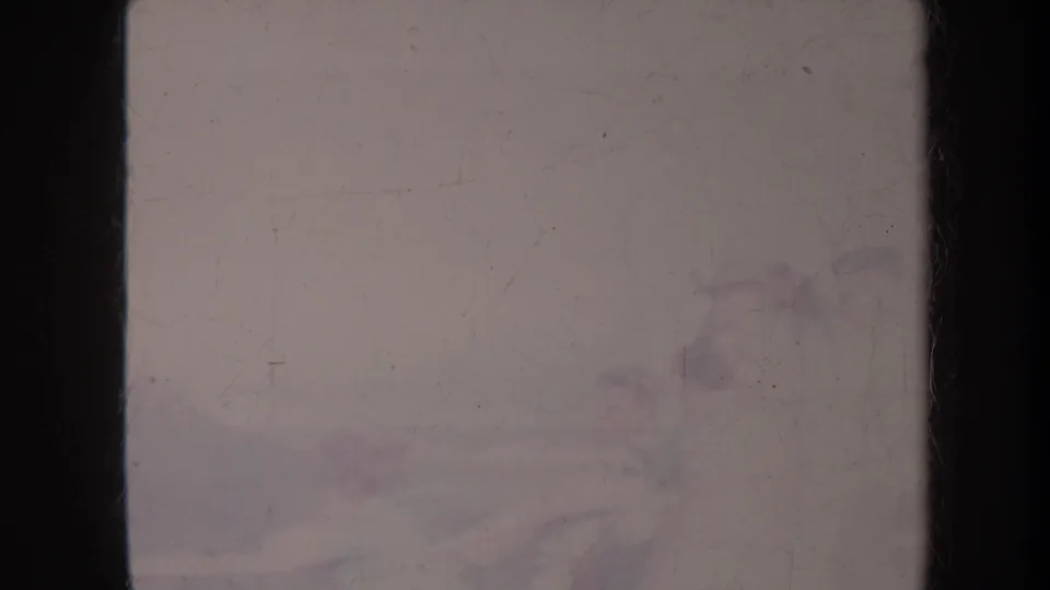 Faded 1967 Honolulu coastal frame showing a pale sky, distant mountains, soft shoreline, and a small dark shape overhead.
