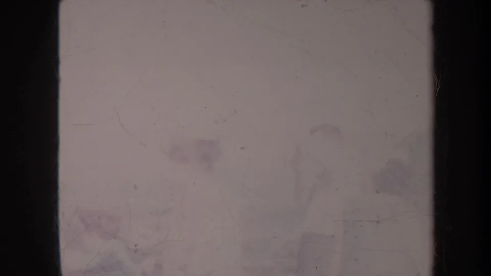 Degraded 8mm Honolulu vacation frame with faint distant people, pale sea tones, dark frame edges, scratches, and heavy fading.