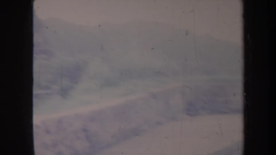 1967 Honolulu 8mm frame with hazy ocean, distant mountain forms, dark film borders, surface scratches, and pink-purple fading.