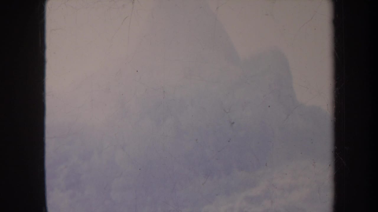 Pale fog and faint mountain forms framed by dark vertical film edges.