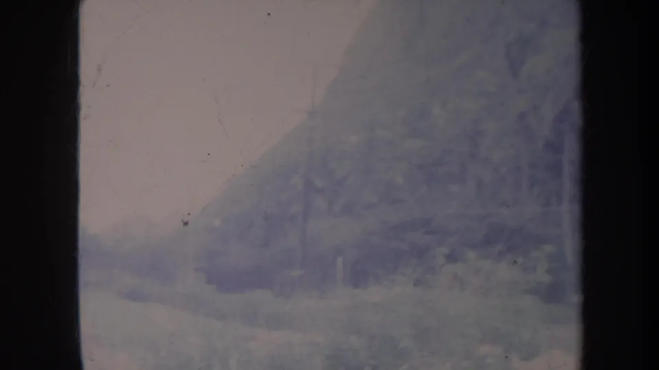 Faded Honolulu-area mountain slope and roadside greenery appear through grain, scratches, and heavy color aging.