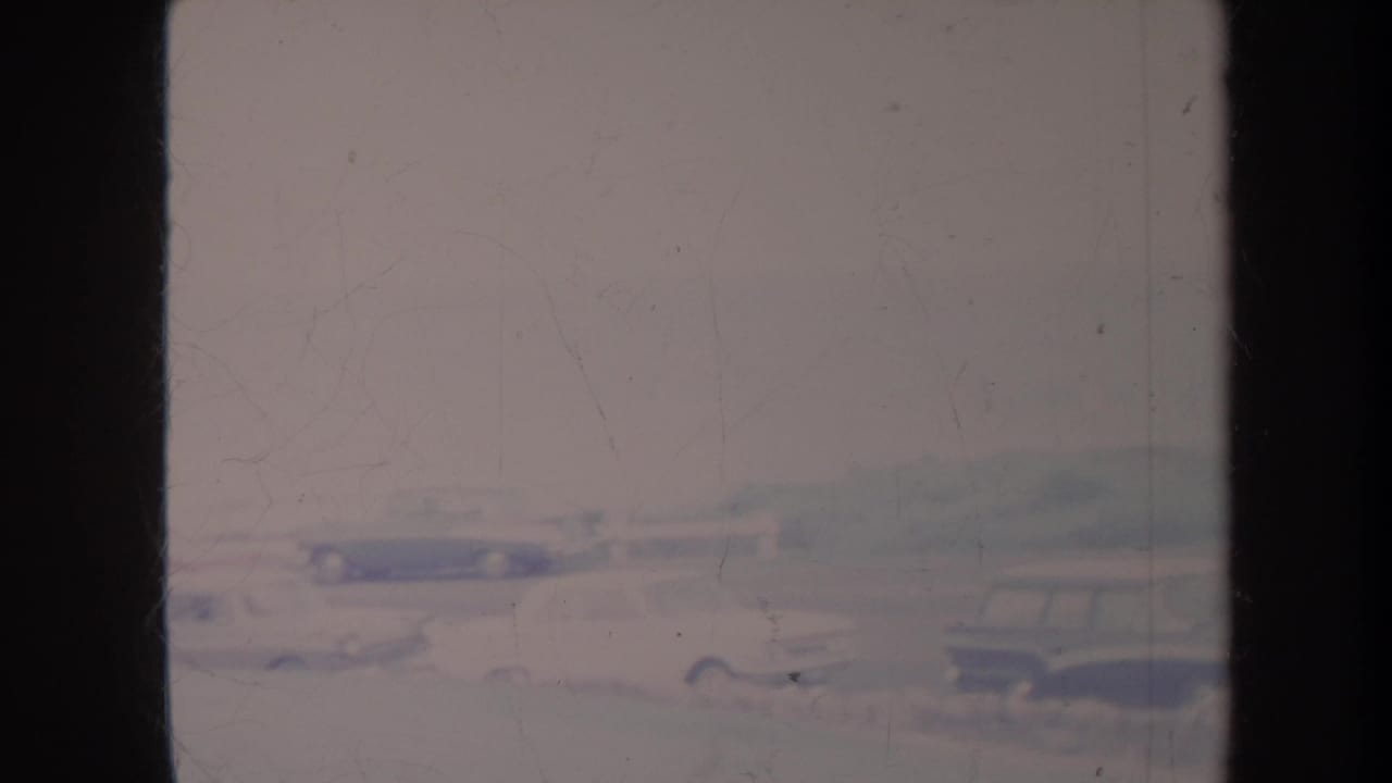 Blurred roadside view with classic cars behind dark vertical frame edges.