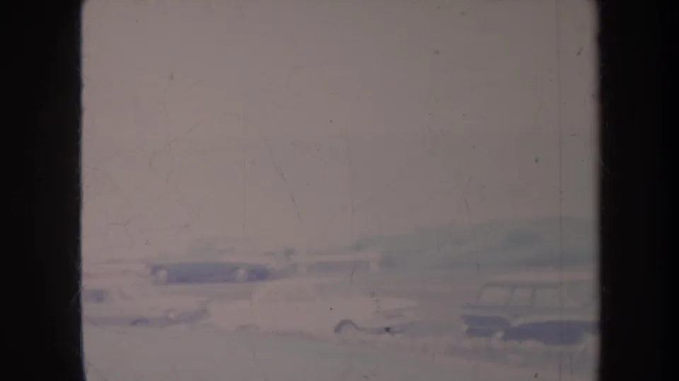 Faded 1967 Honolulu 8mm frame showing classic cars on a road, partly obscured by dark film or window edges.