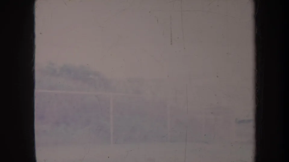 Faded 8mm Honolulu frame showing a pale fence and distant hillside through scratches and dust.
