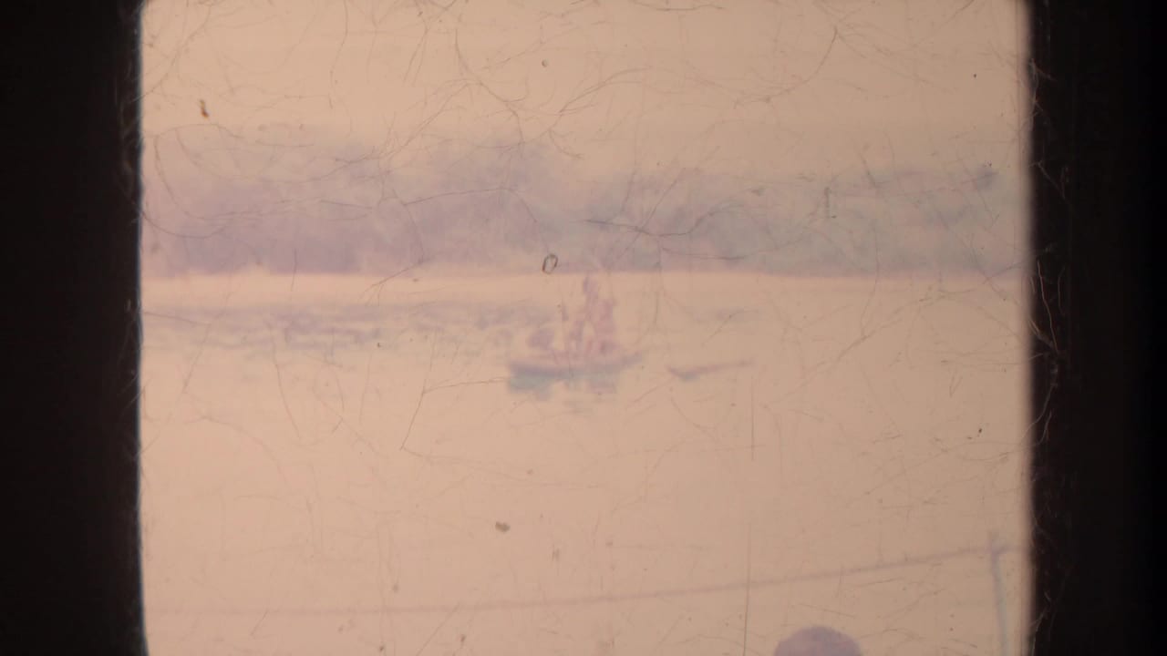 Small distant boat on hazy water beside a dark vertical frame edge.