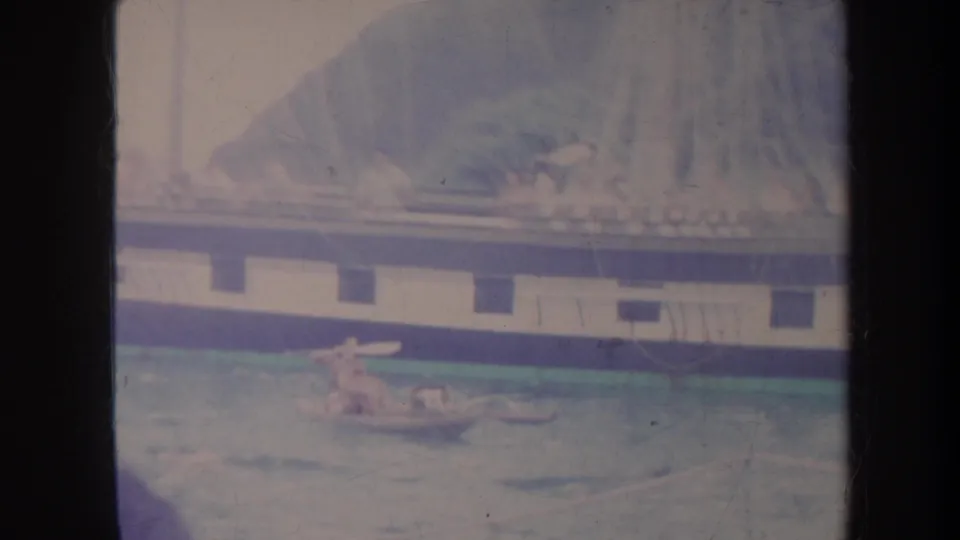 1967 Honolulu waterfront frame with a large vessel in the background and people near a small raft or dinghy in the foreground.