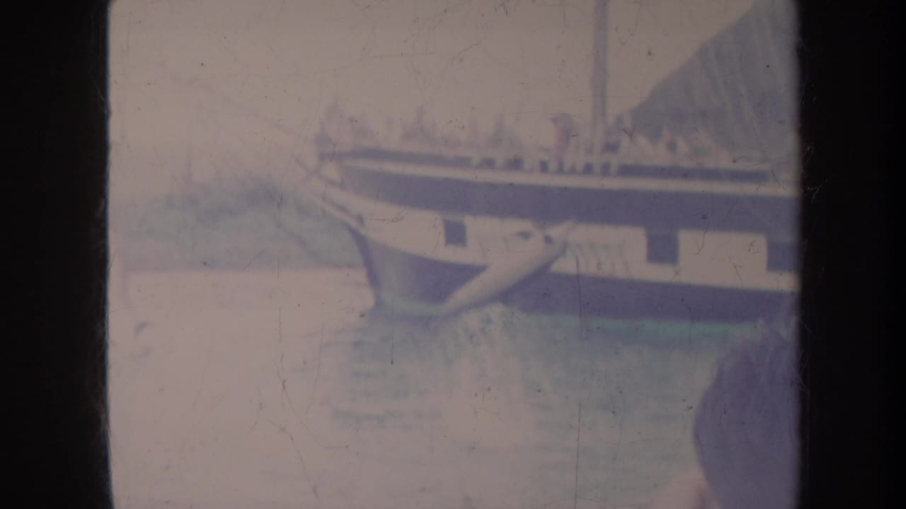 1967 Honolulu frame showing a large passenger vessel with indistinct people, calm water, and a partial person at the edge of the frame.