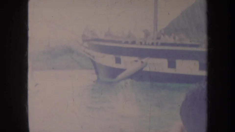 1967 Honolulu frame showing a large passenger vessel with indistinct people, calm water, and a partial person at the edge of the frame.