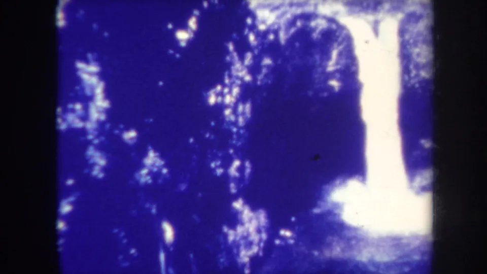 1967 Honolulu 8mm frame showing the waterfall more clearly, bright against dark rock and blue-shifted vegetation.