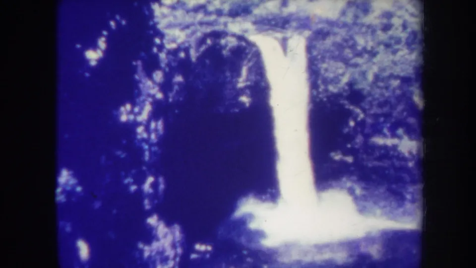 1967 Honolulu 8mm frame holding on the waterfall, with dark surrounding foliage and a glowing splash area below.