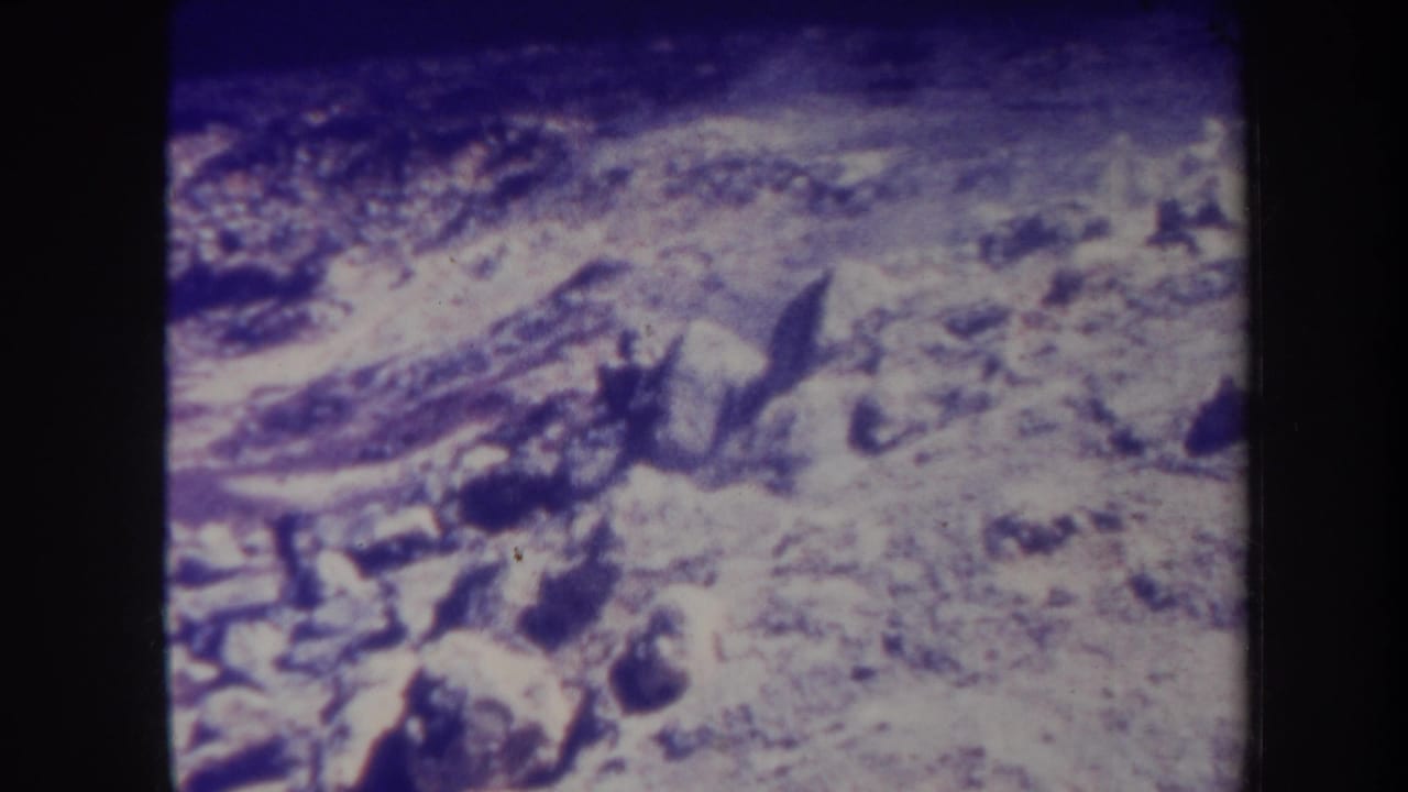 Barren rocky area with scattered dark stones and a low haze over the ground.