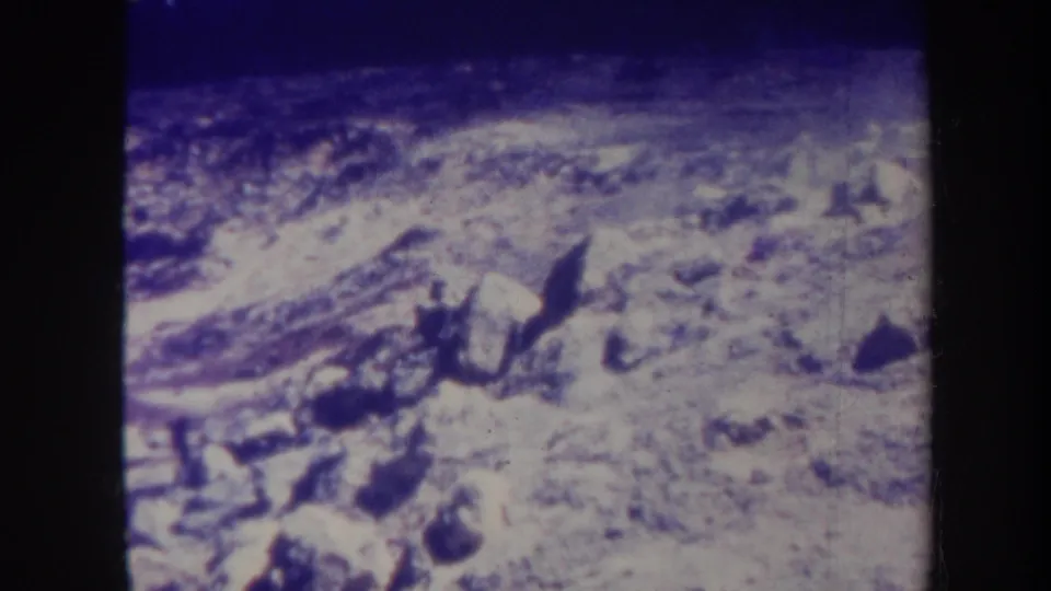 1967 Honolulu 8mm frame showing pale uneven rocks, scattered darker stones, low smoke or haze, and visible dark film borders.