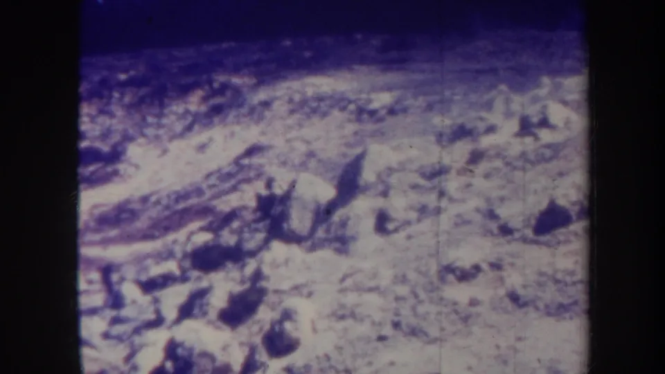 1967 Honolulu home-movie frame of a pale rocky or snowlike slope, softened by 8mm grain and purple-blue color shift.