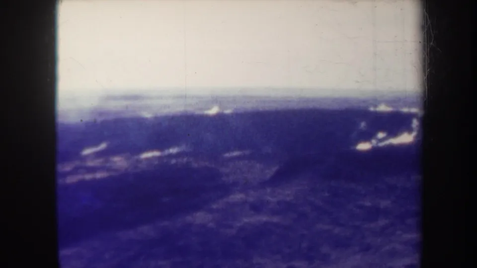 1967 Honolulu-area home-movie frame appears to show blue mountain slopes from above, with pale sky and scattered bright cloud patches.