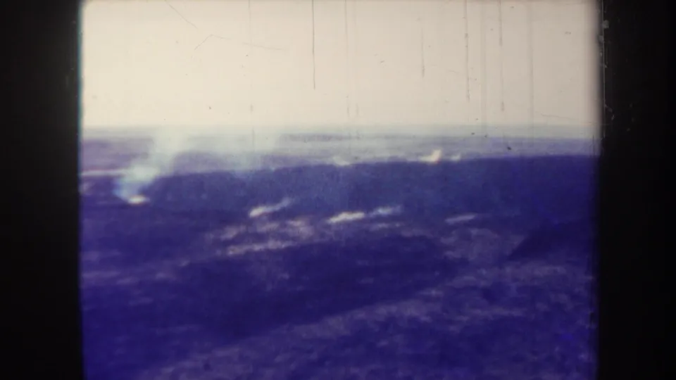 1967 Hawaii 8mm view of smoke drifting above a dark volcanic landscape with faded color and gate edges.