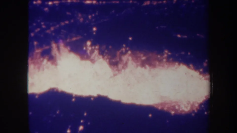 1967 Honolulu 8mm frame showing overexposed flames across the bottom and scattered embers in a blue night scene.