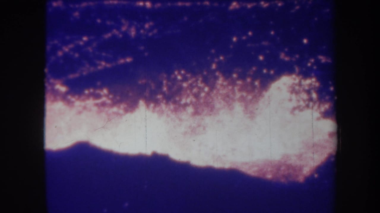 1967 Hawaii 8mm frame of intense volcanic glow or lava-like activity at night, seen through faded color home-movie film.