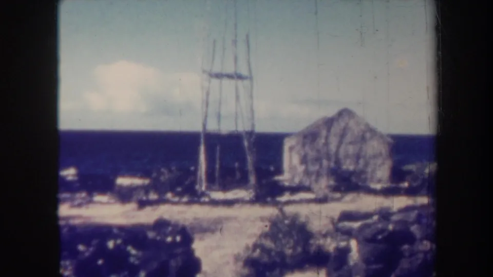 Soft 8mm Honolulu coastal frame with a metal line tower, stone building, rocks, vegetation, and the ocean stretching to the horizon.