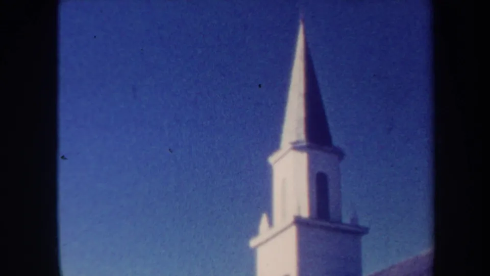 1967 Honolulu frame with a white church-like steeple, partial roofline, saturated blue sky, and visible 8mm texture.