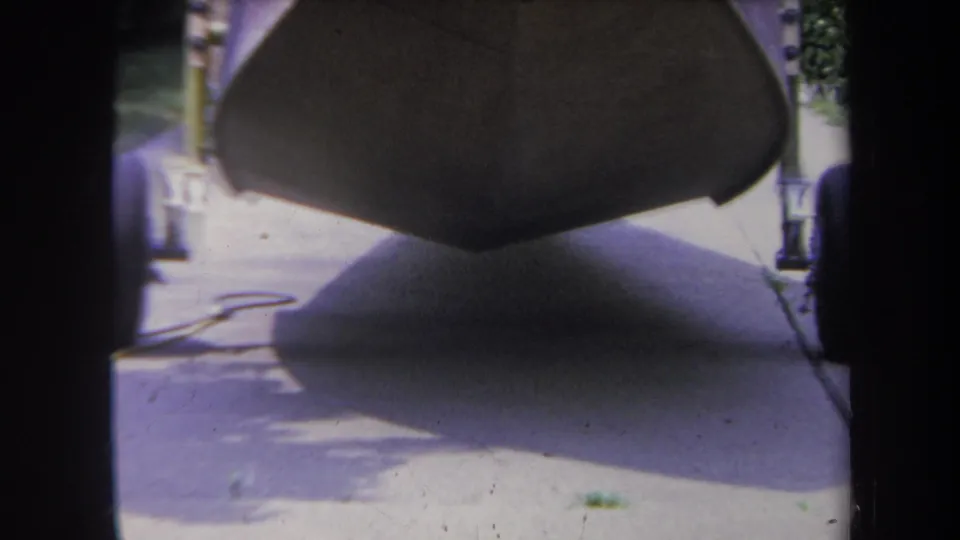 At the end of the approach, the boat bow dominates the frame, with trailer wheels partly visible and the driveway below.